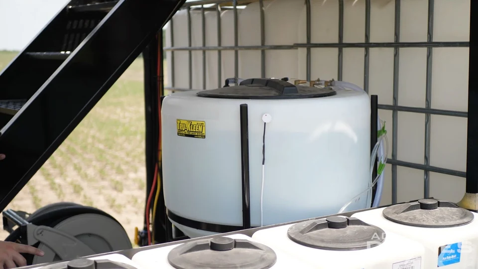 Liquid storage tanks and a hose reel on an agricultural drone support trailer.