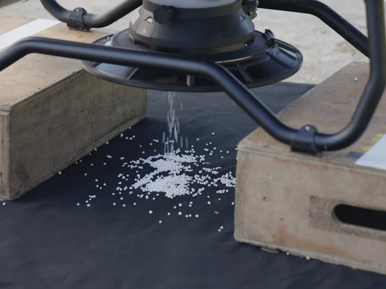 White granules dispensing onto a black collection mat during DJI flow calibration.