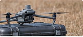 Reference illustration of a drone on its equipment case beside a field